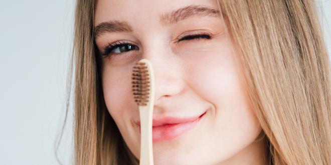 a girl holding a bamboo toothbrush