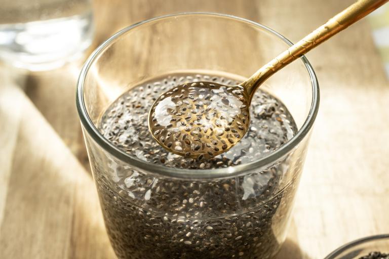 a glass of chia seeds in water, soaking into a gel that collects on a spoon